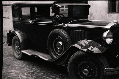 Classic 1929-1931 Ford Model A sedan in black and white. Visible features include the front bumper, fender, running board, an...
