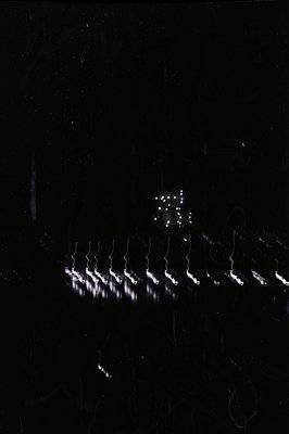 A nighttime scene features multiple long exposure light trails extending into the distance, resembling stylized lightning or ...