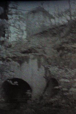 Close-up view of aged stone archway. Texture shows significant weathering and possible moss or lichen growth. Low-light condi...