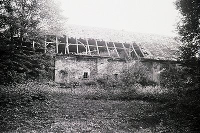 Overgrown ruins of a stone building with a collapsed roof, likely a former farmhouse or small structure. Exposed timber frami...