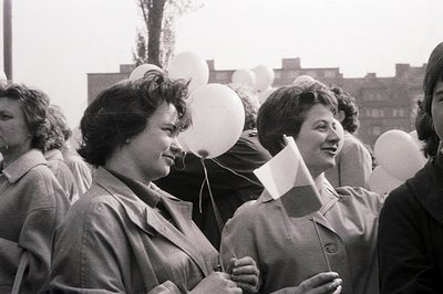 A group of young women, likely in Bulgaria, hold white balloons and flags, seemingly participating in a public event. Archite...