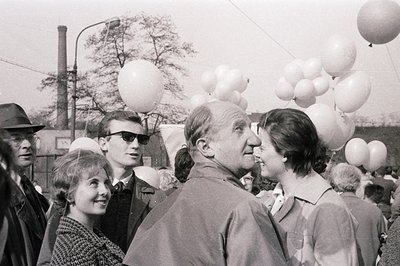 A candid moment captured in black and white: A man in a short-sleeved shirt speaks closely to a woman with a stylish bob. A y...
