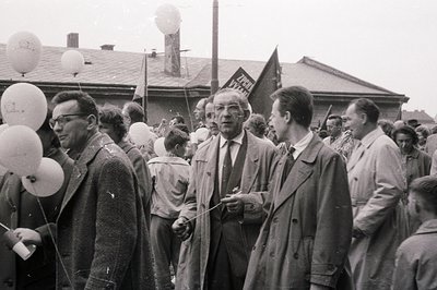 Crowd scene featuring men and boys, likely a rally or public event. Several individuals hold balloons; flags with Cyrillic sc...