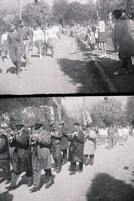 A marching band performs in a town parade, likely a national holiday celebration. Men in uniform play brass instruments, whil...
