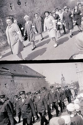 A marching military procession passes a group of women in suits and coats. Likely a parade or official ceremony. Visible arch...