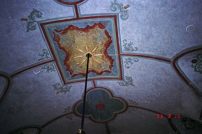 A close-up view of a domed ceiling with elaborate painted details. Features include floral and geometric patterns in shades o...