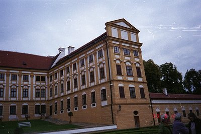 Elegant Baroque palace with mustard-yellow facade and decorative white detailing. Notice the symmetrical window arrangement &...