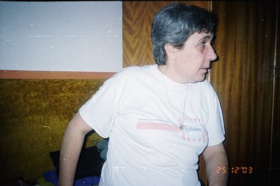 A woman in profile wears a white t-shirt with pink and orange accent stripes and “Eskimo” printed on it. Interior background ...