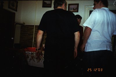 Two men stand in what appears to be a dimly lit room with a vintage billiard table. One wears black, the other white. Several...