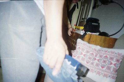 Close-up photo captures a person in a grey sweater holding blue denim fabric. A patterned textile, possibly embroidered, lies...