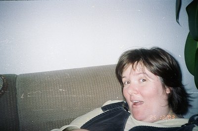 Close-up of a person with dark hair and bangs, displaying an expressive facial gesture. The photo, taken on an early digital ...