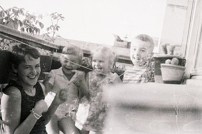 Four children, likely siblings, pose on a rooftop terrace or balcony. The group includes a young woman and three boys, all sm...