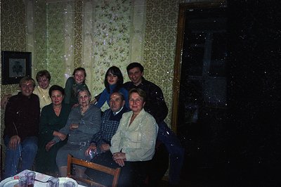 Family portrait from a domestic interior, circa 1970s. Seven people are seated around a table. Floral wallpaper and dated dec...