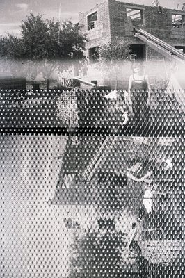 A blurred, grainy image shows a partial view of construction work in progress. A two-story building under construction domina...
