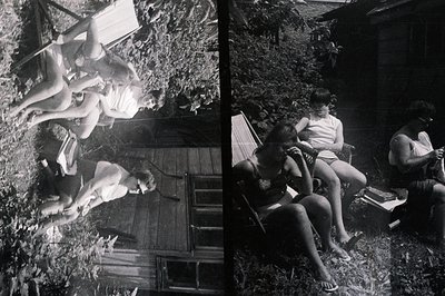 Black and white photo capturing a casual gathering outdoors, likely a backyard or patio area. Three young women are seated on...