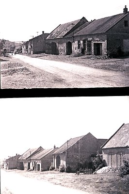 Monochrome view of rural buildings with corrugated iron roofs, likely agricultural or industrial structures. A dirt road runs...