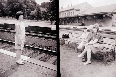 A young girl in a short dress stands near train tracks; two other girls sit on a bench at a simple, vintage railway station p...