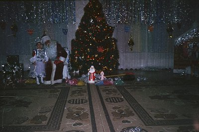 Festive scene depicting two figures dressed as Santa Claus flanking a decorated Christmas tree, likely a staged holiday event...