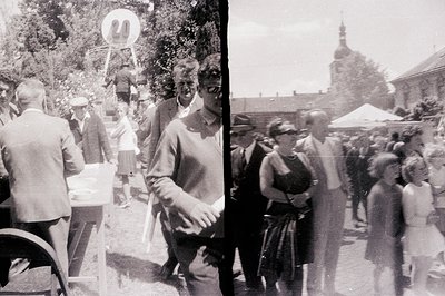 A blurred, candid view of a public gathering, likely a festival or parade. Individuals in mid-1960s attire – dresses, suits –...
