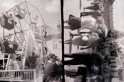 Vintage snapshot captures a bustling fairground scene. A large, vintage carousel dominates the view with riders visible in su...