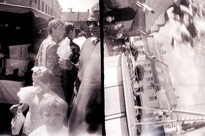 A blurred, candid photo captures a street vendor selling cotton candy, alongside a child gazing upwards. Appears to be a bust...