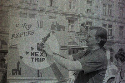A young person, likely a student, appears to be writing or drawing on a storefront window. The text "eko" "EXPRES" and "NEXT ...