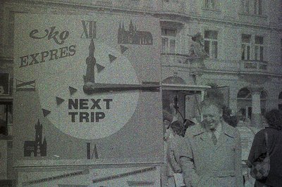 Image shows a bustling city street scene with a prominent display advertising "Next Trip," likely a promotional event. The ar...