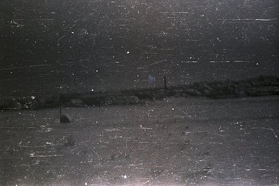 Striated, dark gray surface with a faint horizontal band and several light dots. Appears to be a textured film or photographi...