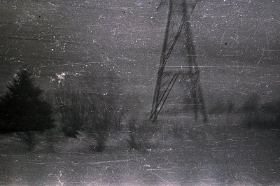 A stark, monochrome photograph depicts a tall, slender structure—likely a radio tower or similar antenna—emerging from a blur...