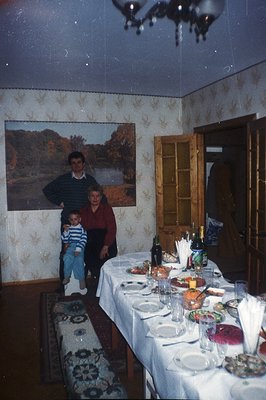 A family gathering is captured in this 1970s-era photograph. A man and a young child sit beside a woman seated at a long tabl...