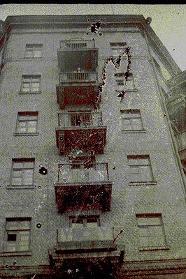 Overhead view of a multi-story building featuring balconies with ornate railings. Possible residential structure. Appears dam...