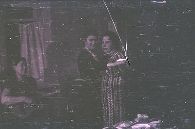 A formal portrait depicting a man in a suit and a woman in a patterned dress; both appear distressed. A partially visible fig...