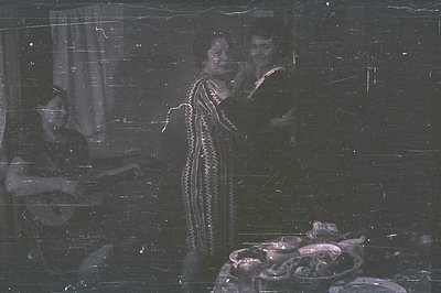 A group portrait, likely staged, featuring three individuals in what appears to be a home setting. Two women are centrally po...