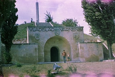 A bunker inscribed "Vladislao Varnensi" stands atop a grassy embankment, likely a defensive structure. Two boys are pictured ...