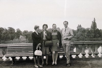 Formal portrait of four individuals posed outdoors, likely near a body of water. Fashion suggests the mid-1960s, with tailore...