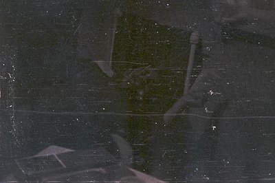 A heavily scratched and marked photographic negative displays faint, distorted imagery. Traces of architectural elements & a ...