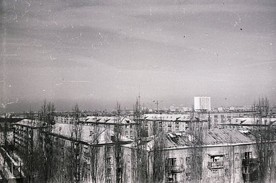 A high-angle view captures a densely populated urban landscape. Apartment buildings with flat roofs and balconies dominate th...
