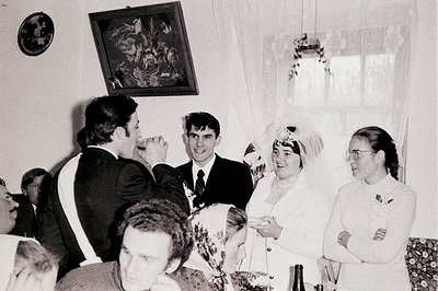 A joyous wedding scene captures a moment of laughter. The bride, adorned with flowers, is beaming as a man in a suit playfull...