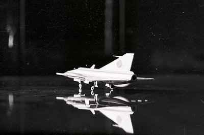 A black and white studio shot of a Japanese Mitsubishi T-2 jet trainer model. The aircraft, with its distinctive tail marking...