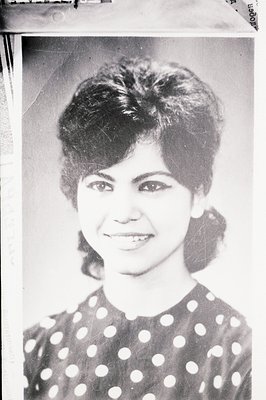 Classic portrait of a young woman with a striking, layered hairstyle and a bright smile. She wears a dark, polka-dot patterne...