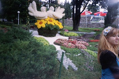 A large floral display features a sculpted bird motif, surrounded by blooming flowers and greenery. A young woman wearing a f...