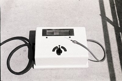 A wall-mounted public telephone, likely from the mid-20th century, features a rectangular viewing window and a coin slot. A c...