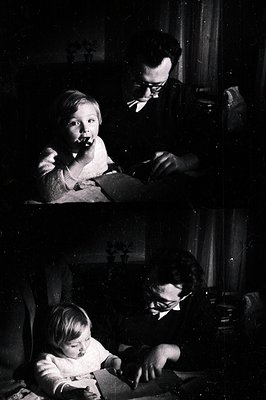 A young child sits on a lap, seemingly engrossed in a book being read by an adult wearing glasses and a bow tie. Interior sce...