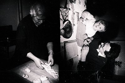 A candid black & white photo captures a multigenerational moment. An older woman kneads dough on a wooden table, surrounded b...