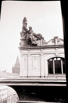 Ornate building facade features a statue atop a decorative cornice. Intricate carvings adorn the structure, with large arched...