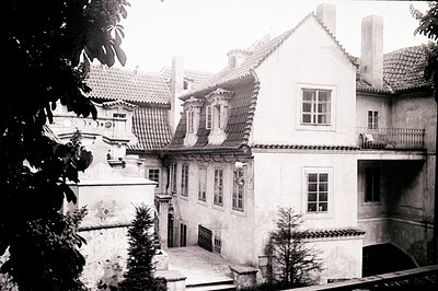 A multi-level residential building with a steeply pitched, tile roof. Features include a small courtyard, exterior staircase,...