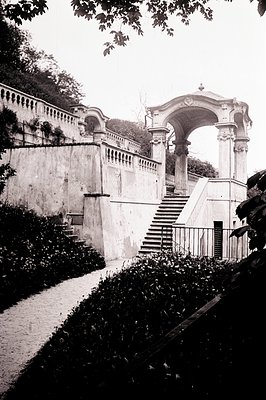 Formal garden terrace with stone steps ascending to a classical pavilion. Architectural detail includes balustrades, columns,...