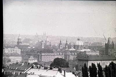 Elevated view of Prague’s cityscape, showcasing a complex of Baroque and Gothic architecture. Dominating the scene are St. Ni...