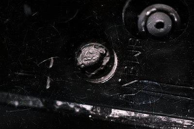 Close-up, black and white photograph captures detail of corroded metal with visible rivets and surface texture. Evidence of s...