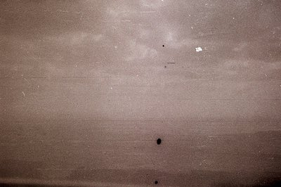 Vintage photograph showing textured, distressed paper surface with dark speckling and light scratches. Likely a film negative...